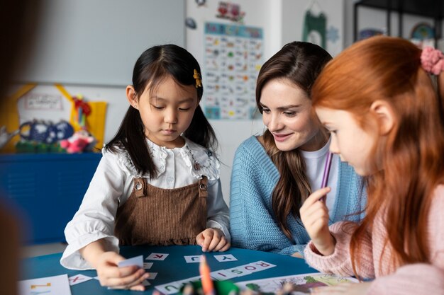 Mittlere Aufnahme von Kindern und Lehrern am Tisch