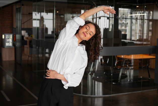 Kostenloses Foto mittlere einstellung einer frau, die sich bei der arbeit dehnt