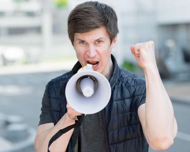 Mittlere Einstellung eines Mannes mit Megaphon, der auf der Straße protestiert