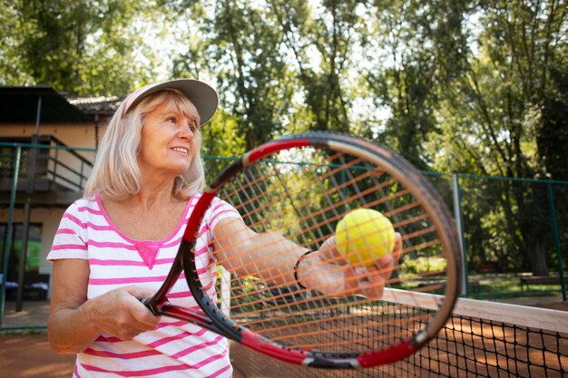 Mittlere geschossene ältere Frau, die Tennis in der Natur spielt
