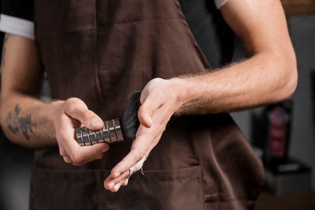 Mittlere Schnittansicht der Hand eines Friseurs mit Rasierpinsel