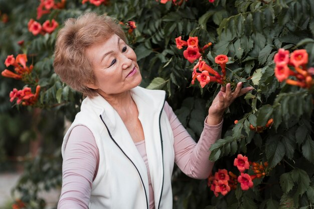 Mittlere Schuss alte Frau, die mit Blumen aufwirft