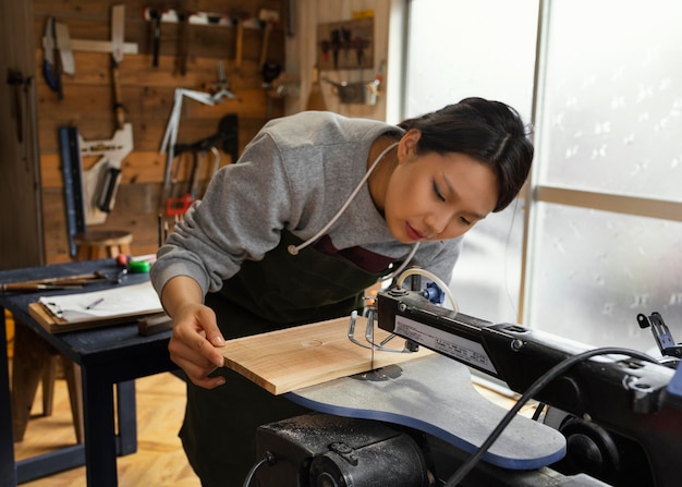 Mittlere Schuss asiatische Frau, die mit Holz arbeitet