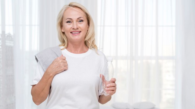 Mittlere Schuss glückliche Frau mit Handtuch und Wasserflasche