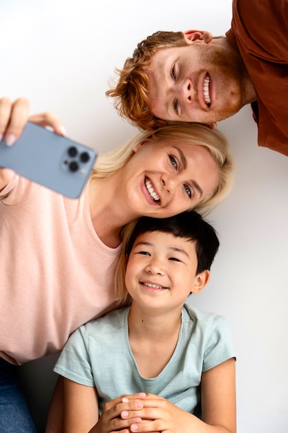 Kostenloses Foto mittlere schuss-smiley-familie, die selfie nimmt