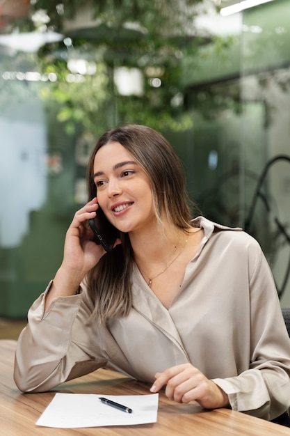 Mittlere Schuss-Smiley-Frau, die am Telefon spricht