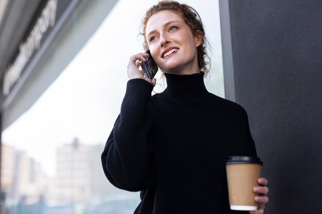 Mittlere Schuss-Smiley-Frau, die am Telefon spricht