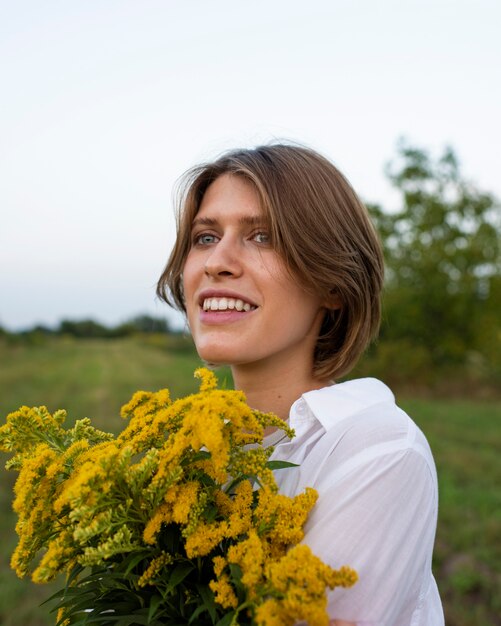 Mittlere Schuss-Smiley-Frau, die Blumen hält