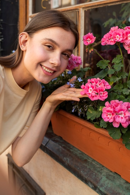 Mittlere Schuss-smiley-Frau, die mit Blumen aufwirft
