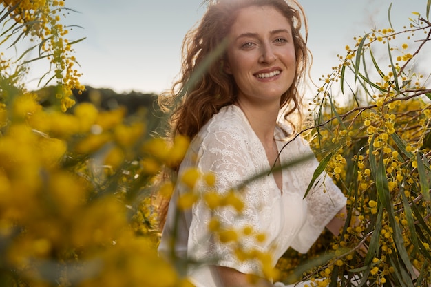 Mittlere schuss-smiley-frau, die mit steppenblume aufwirft