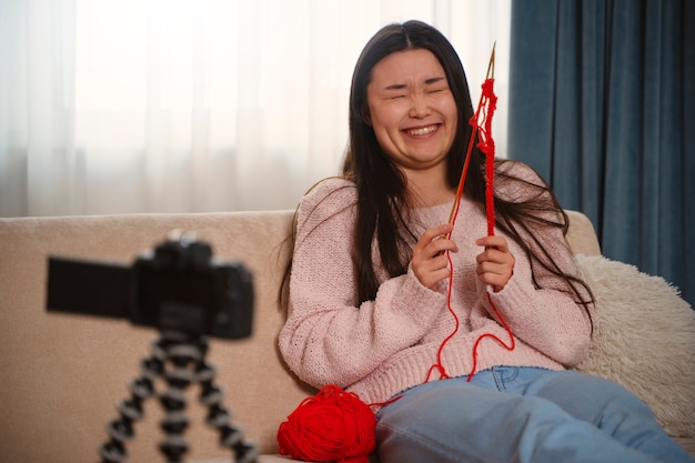 Mittlere Schuss-smiley-Frau, die strickt