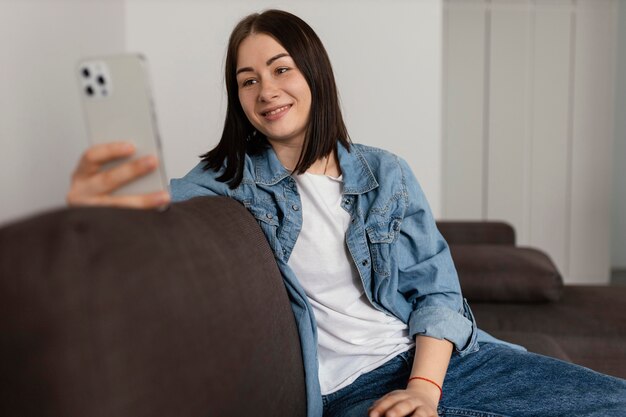 Mittlere Schuss-Smiley-Frau, die Telefon hält