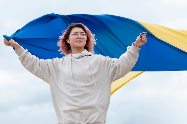 Mittlere schuss-smiley-frau, die ukrainische flagge hält