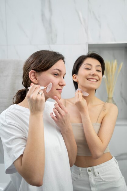 Mittlere schuss-smiley-frauen, die gua sha-werkzeuge verwenden