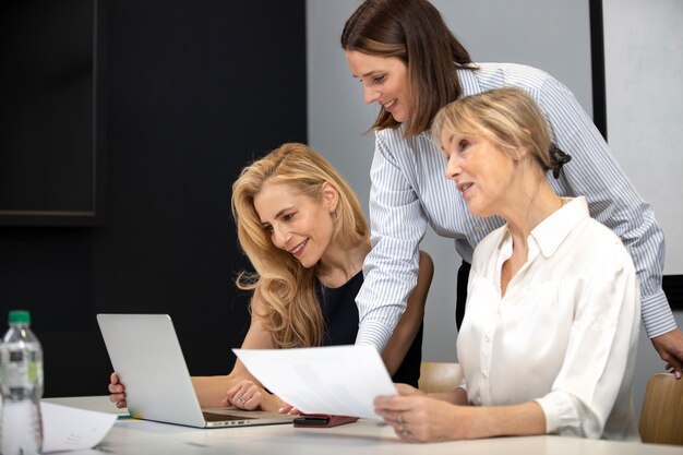 Mittlere Schuss-Smiley-Frauen, die mit Laptop arbeiten