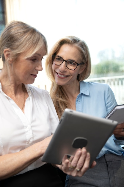 Mittlere Schuss-Smiley-Frauen, die mit Tablet arbeiten