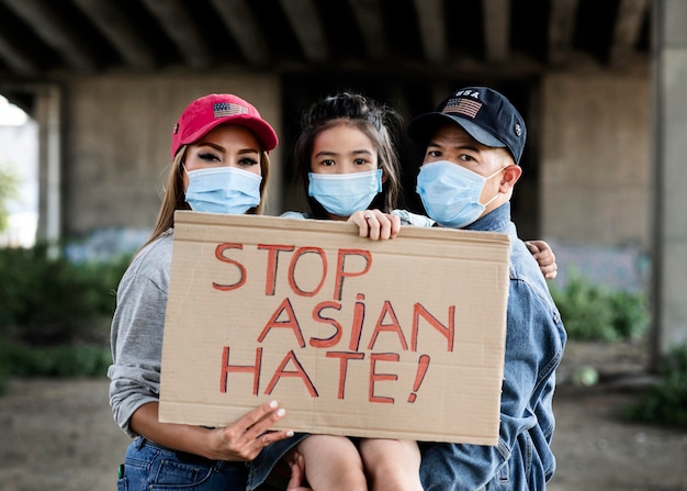 Kostenloses Foto mittlere schussfamilie mit plakat und gesichtsmaske