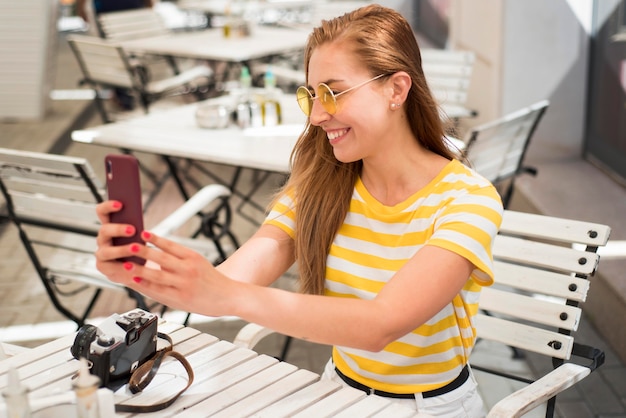 Mittlere Schussfrau am Tisch, die selfie nimmt