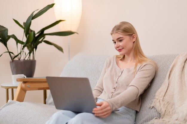 Mittlere Schussfrau auf Couch mit Laptop