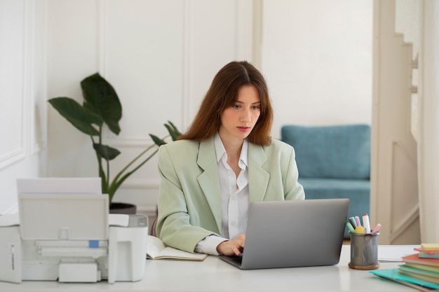 Mittlere Schussfrau, die am Laptop arbeitet