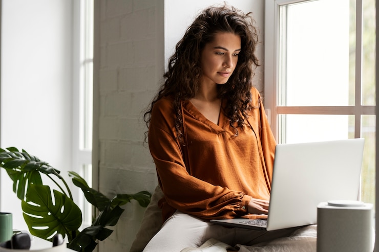 Kostenlose Foto mittlere schussfrau, die am laptop arbeitet