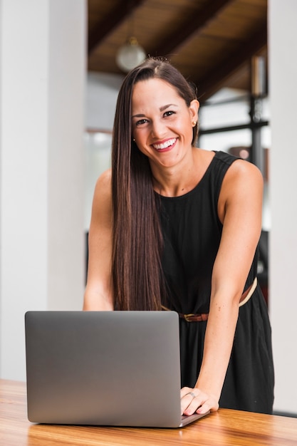 Mittlere Schussfrau, die am Laptop lächelt und arbeitet