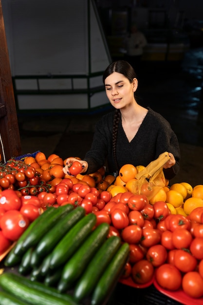 Kostenloses Foto mittlere schussfrau, die am markt einkauft