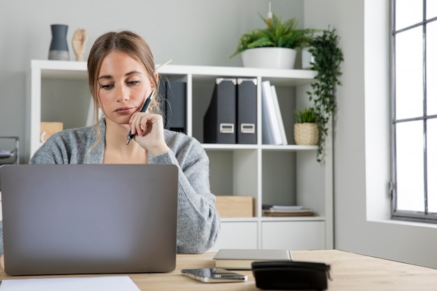 Mittlere Schussfrau, die am Schreibtisch arbeitet