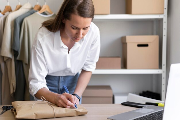 Mittlere Schussfrau, die auf Paket schreibt