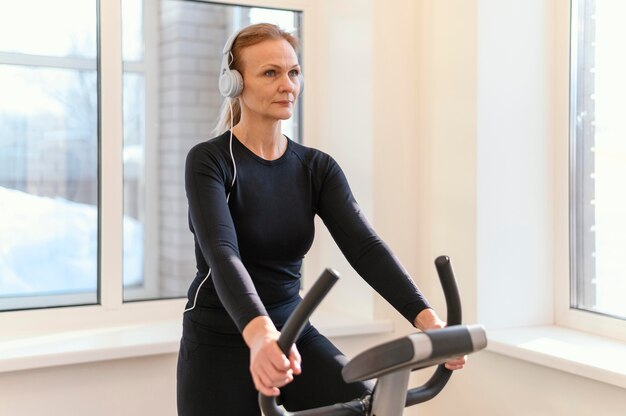 Mittlere Schussfrau, die auf Spinbike trainiert