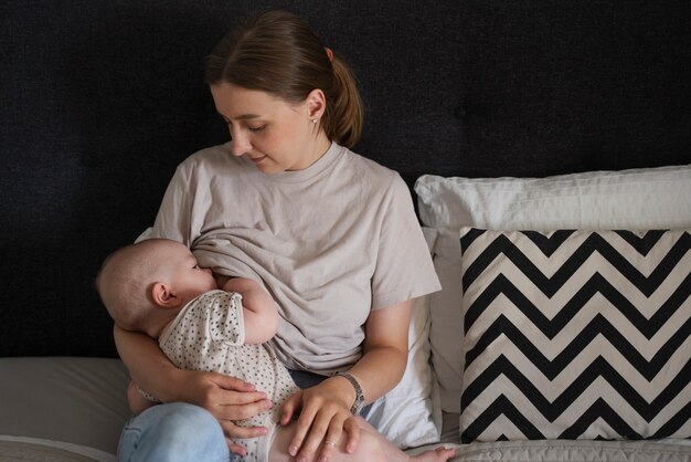 Mittlere Schussfrau, die Baby im Bett stillt