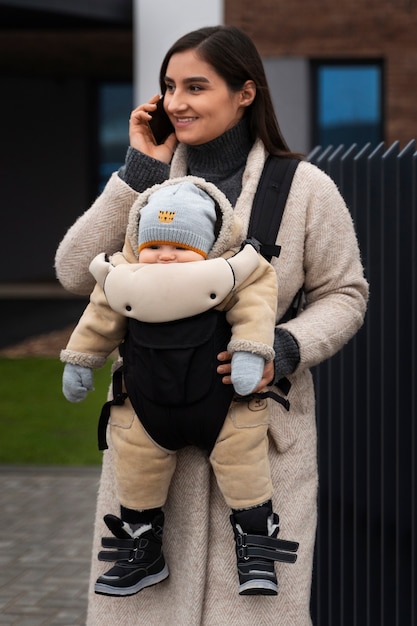 Mittlere Schussfrau, die Baby in Träger hält