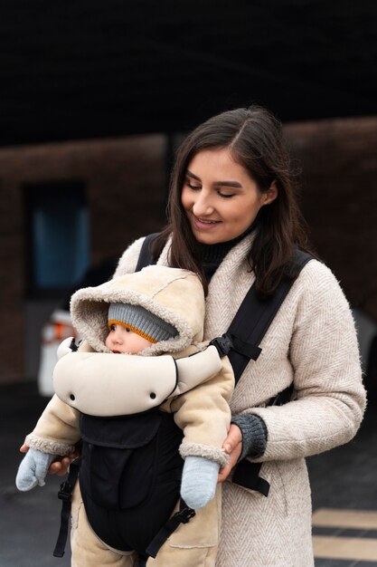 Mittlere Schussfrau, die Baby in Träger hält