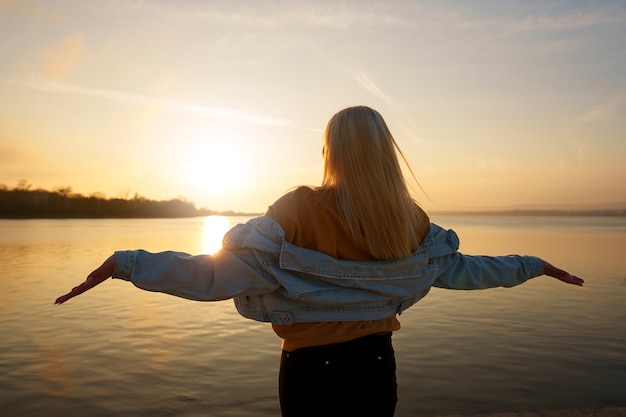 Kostenloses Foto mittlere schussfrau, die bei sonnenuntergang aufwirft