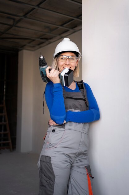 Mittlere Schussfrau, die Bohrmaschine bei der Arbeit hält