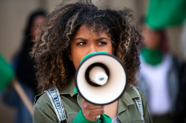 Kostenloses Foto mittlere schussfrau, die draußen protestiert