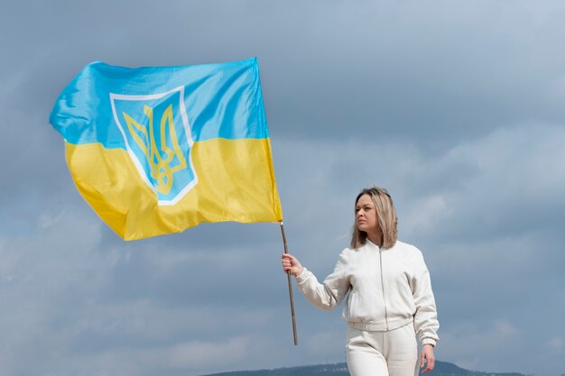 Mittlere Schussfrau, die draußen ukrainische Flagge hält