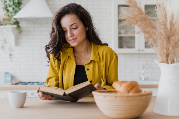 Mittlere Schussfrau, die ein Buch am Tisch liest