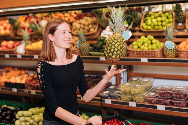 Mittlere Schussfrau, die eine Ananas in die Luft wirft