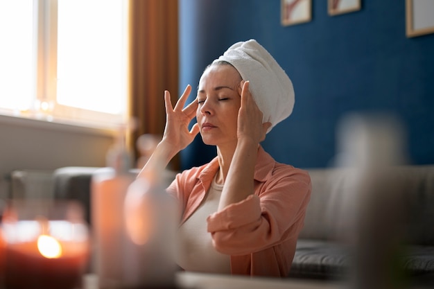 Kostenloses Foto mittlere schussfrau, die gesichtsyoga praktiziert