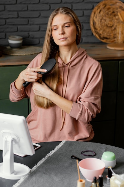 Kostenloses Foto mittlere schussfrau, die haare bürstet