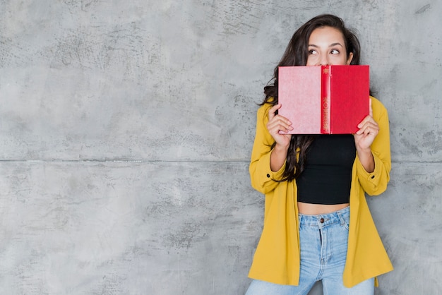 Mittlere Schussfrau, die ihr Gesicht mit Buch bedeckt