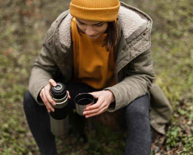 Kostenloses Foto mittlere schussfrau, die im wald sitzt