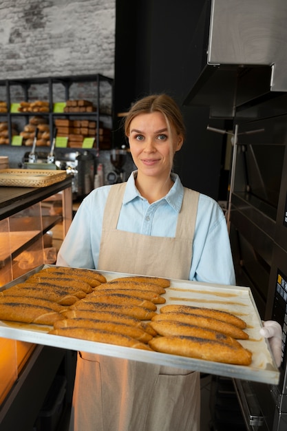 Kostenloses Foto mittlere schussfrau, die in der bäckerei arbeitet