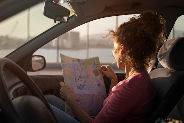 Mittlere Schussfrau, die Karte im Auto hält