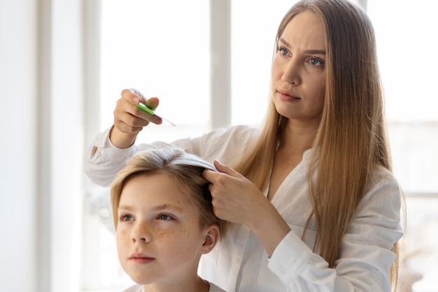 Kostenloses Foto mittlere schussfrau, die kind mit läusen hilft