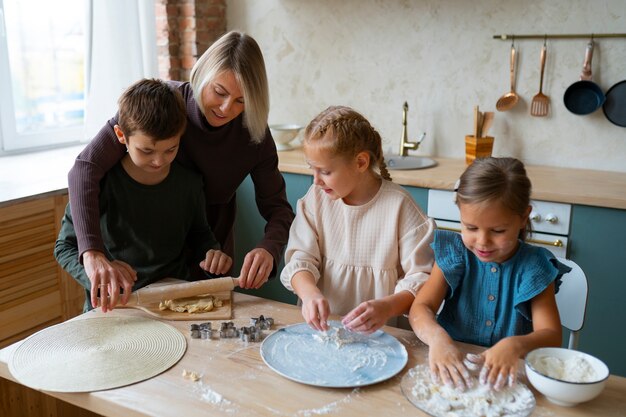 Mittlere Schussfrau, die Kindern beim Kochen hilft