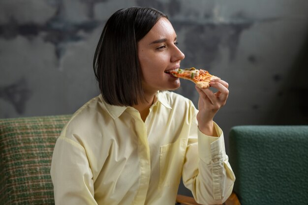 Mittlere Schussfrau, die köstliche Pizza isst