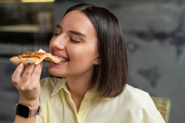 Mittlere Schussfrau, die köstliche Pizza isst