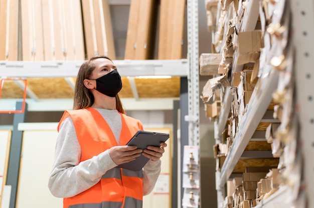 Kostenloses Foto mittlere schussfrau, die maske am arbeitsplatz trägt